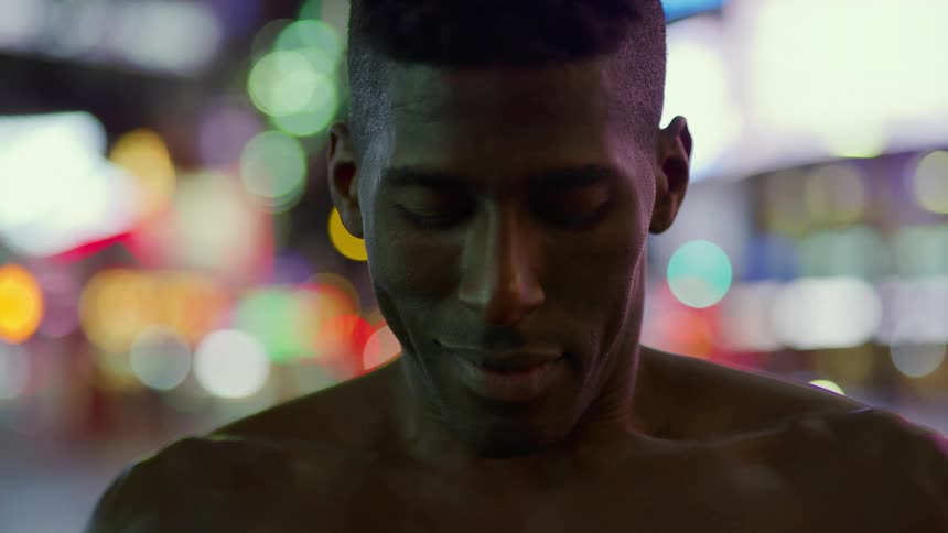 A man is in an urban area takes a breath and looks at the camera
