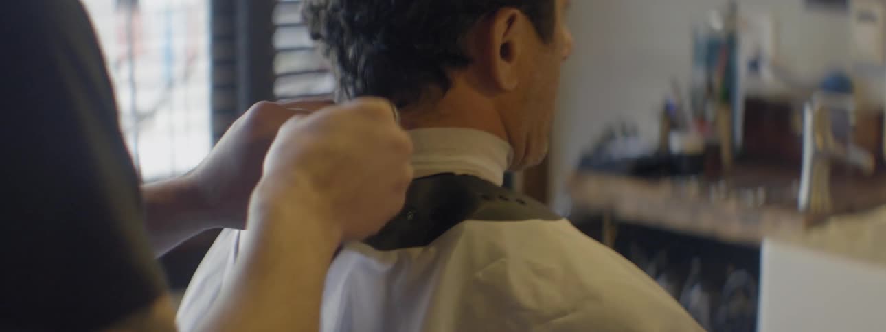 A barber ties a cloth around a man's neck