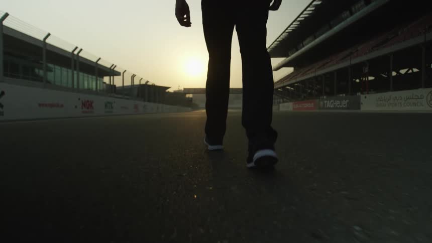 A man walks along a racetrack in an empty stadium
