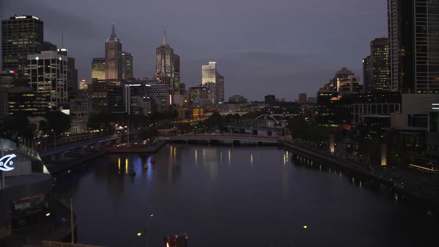 Traffic crosses bridges over river running through city as water reflects city lights