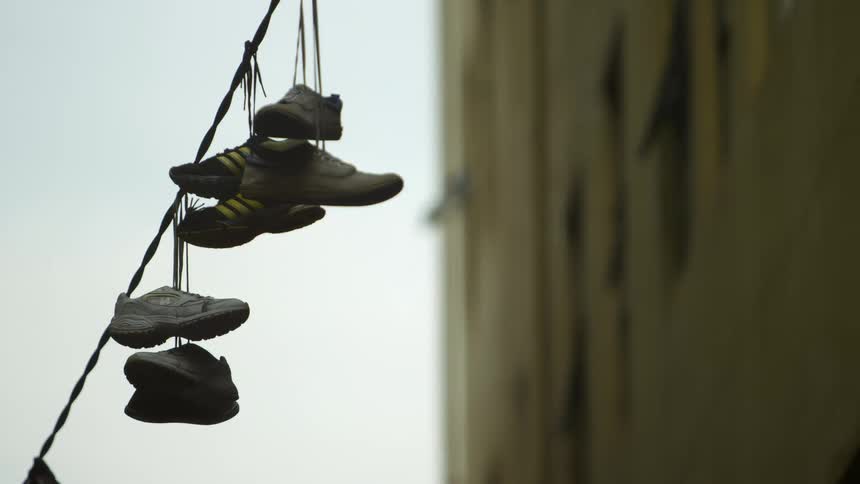 Shoes hanging by their shoelaces from an electric line near a building