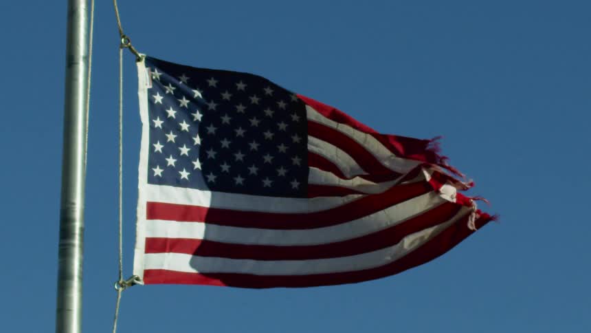 An american flag is moving in the wind on a clear day