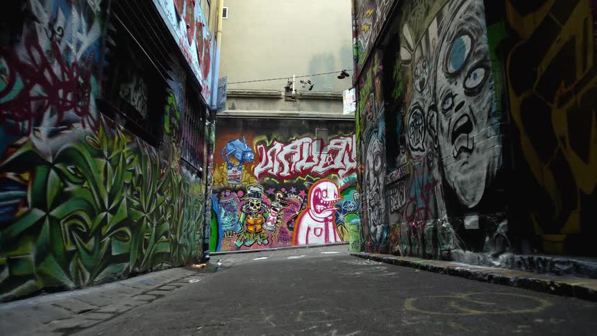 Graffiti covers walls of buildings on all side of intersection under cloudy sky