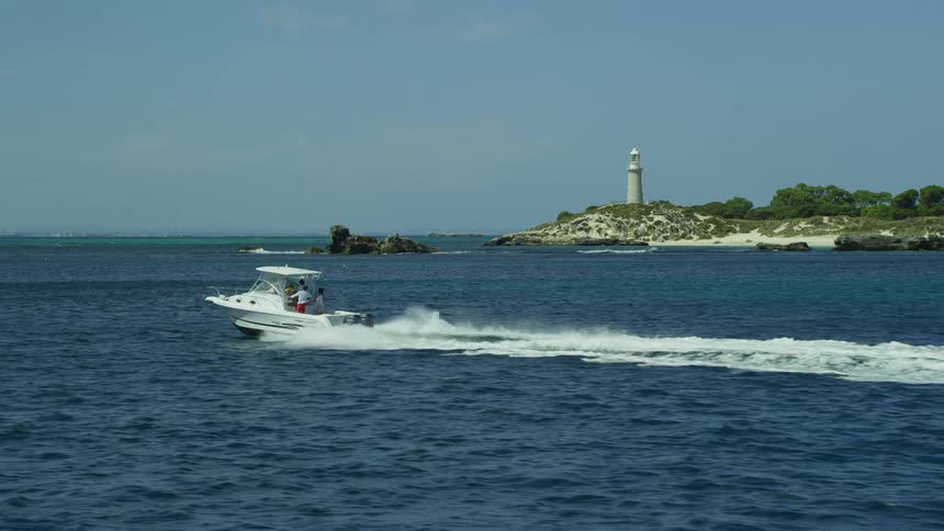 A lighthouse is in the background as a vessel makes its way out to sea