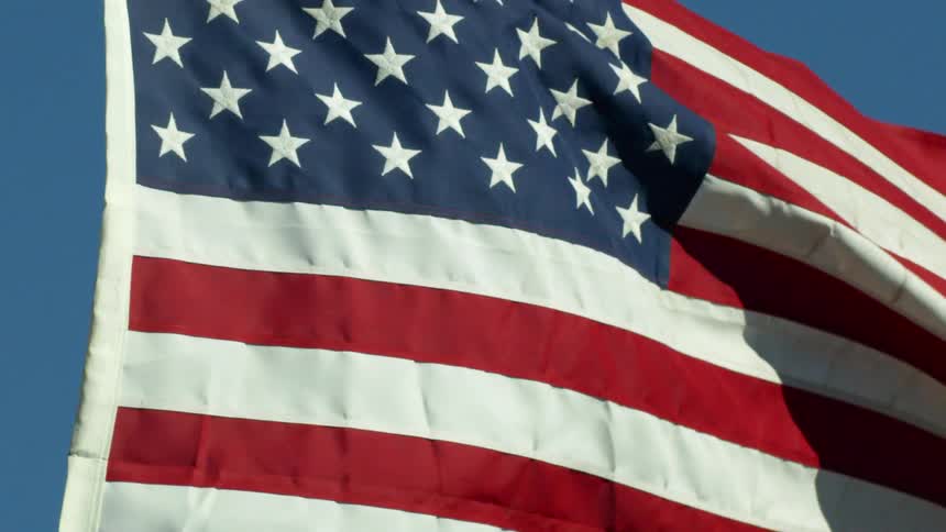 An american flag waving in the wind with the sky and the background