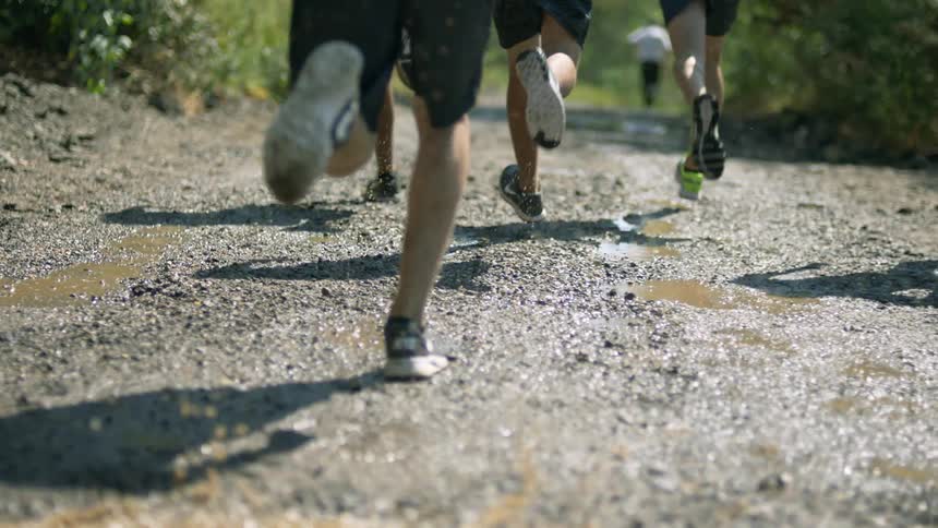 People with sneakers running on a dirt road with water mud and gravel