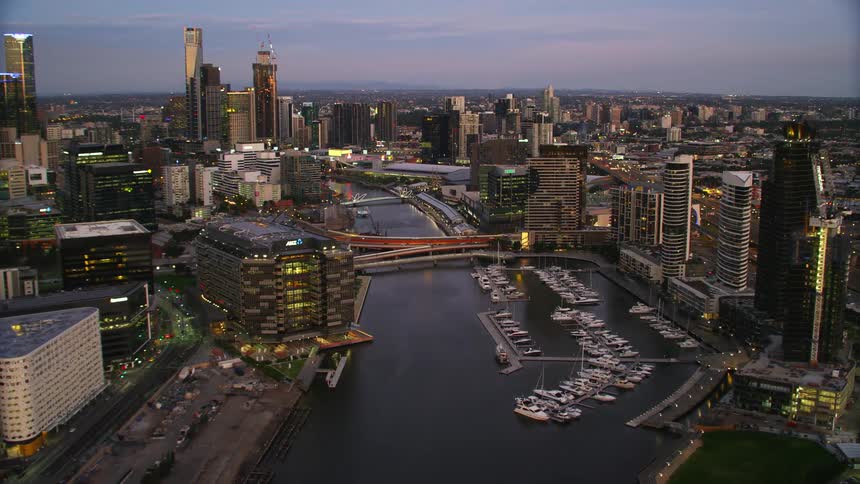 Boats line the waterfront of a river that flows through a city