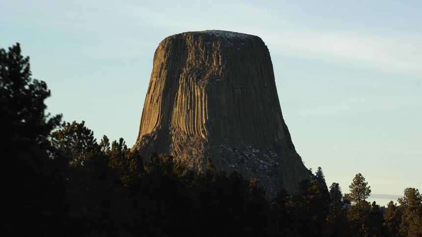 A tall mesa sits behind a line of trees