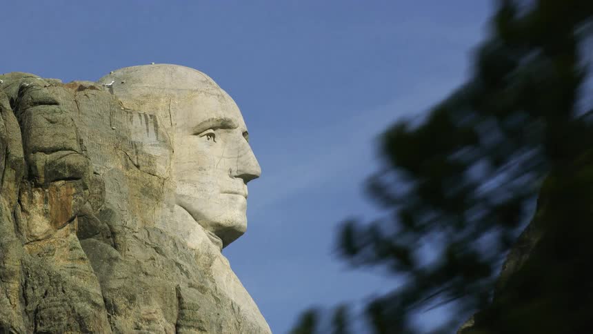 A partial view of mt rushmore as seen from a vehicle driving away in the daytime
