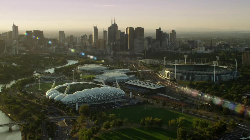 A river winding through a city with tall buildings and sports stadiums at dusk