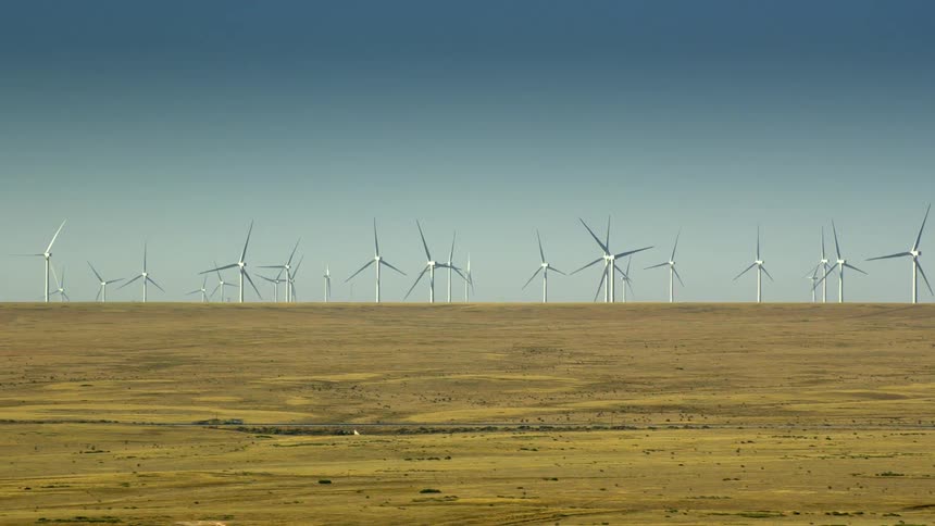 Rotating wind turbines in a rural field on a clear day