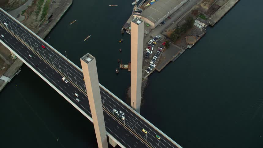 Vehicles are traveling across a bridge over a shipping bay
