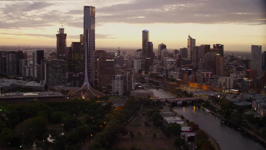 A city skyline with buildings a river and trees with the sky and clouds in the background
