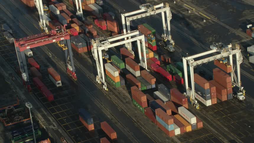 Aerial view of colorful shipping containers piled under cranes at port in the morning