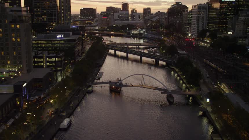 A city skyline with buildings a river and trees with the sky and clouds in the background