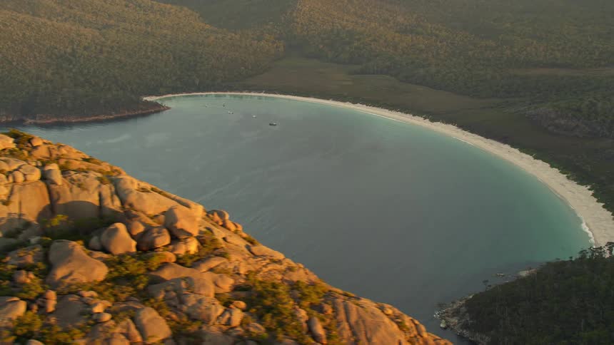 Aerial view of a beach behind a rocky mountain at evening