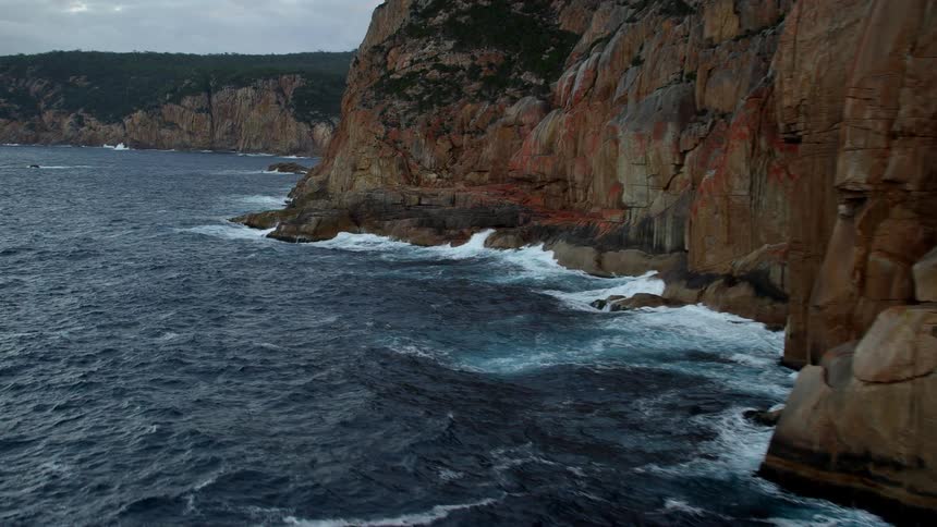 Aerial view of ocean waves crashing on the coastal cliffs at morning