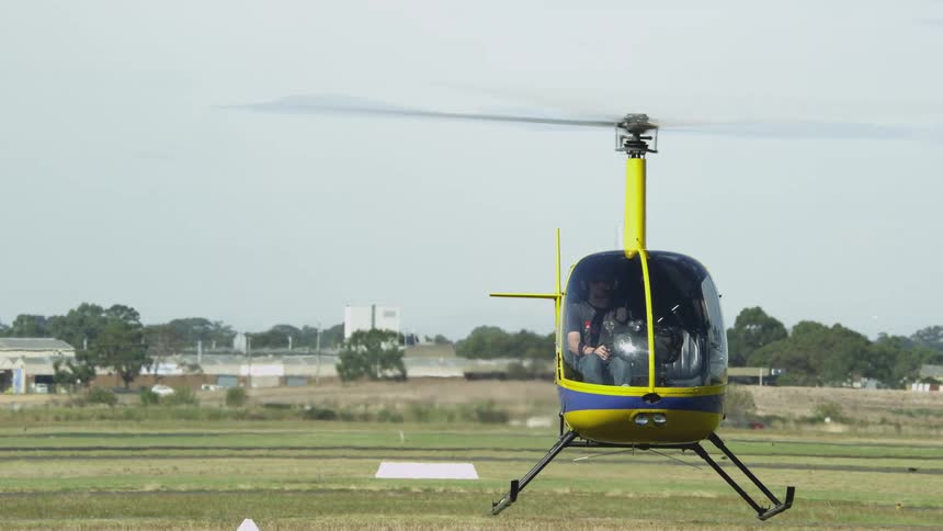 A helicopter hovers over the ground as it lands