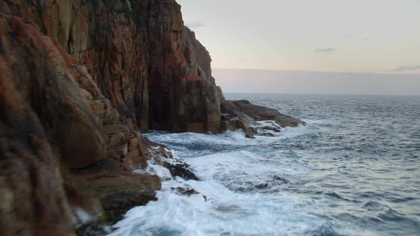 A rocky coast with waves with the sky and clouds in the background