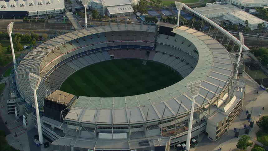 A stadium with grass field surrounded by spotlights and trees