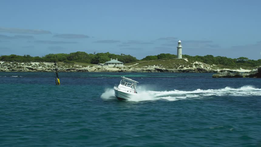A speed boat navigates a turn in the ocean just off the coast