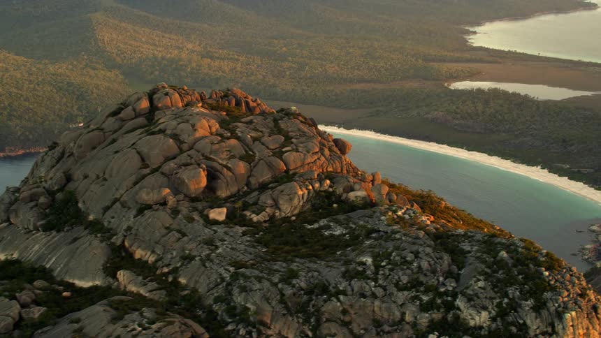 Aerial view of a mountain in front of a beach at sunset