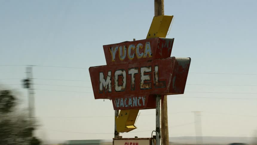 An old motel sign and nearby buildings