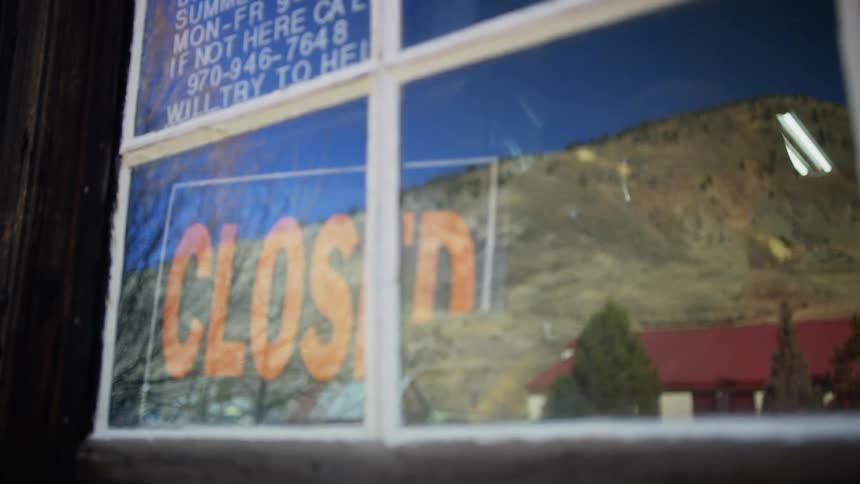 Someone inside a business changes the sign in the window from open to closed