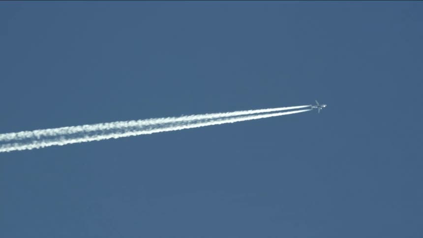 A plane flying in the sky with chemtrails