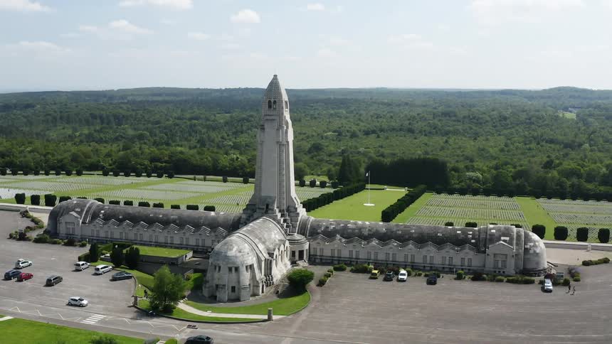 People walk past a large monument at a military cemetery