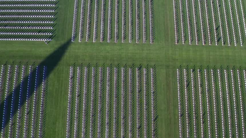 A cemetery with grass trees and white crosses