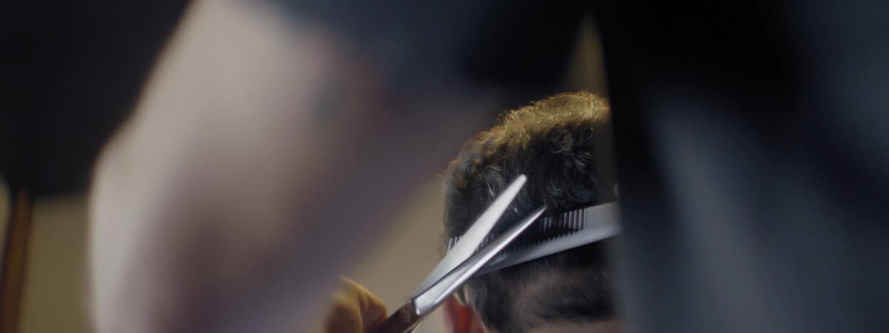 A barber combs and clips a man's hair
