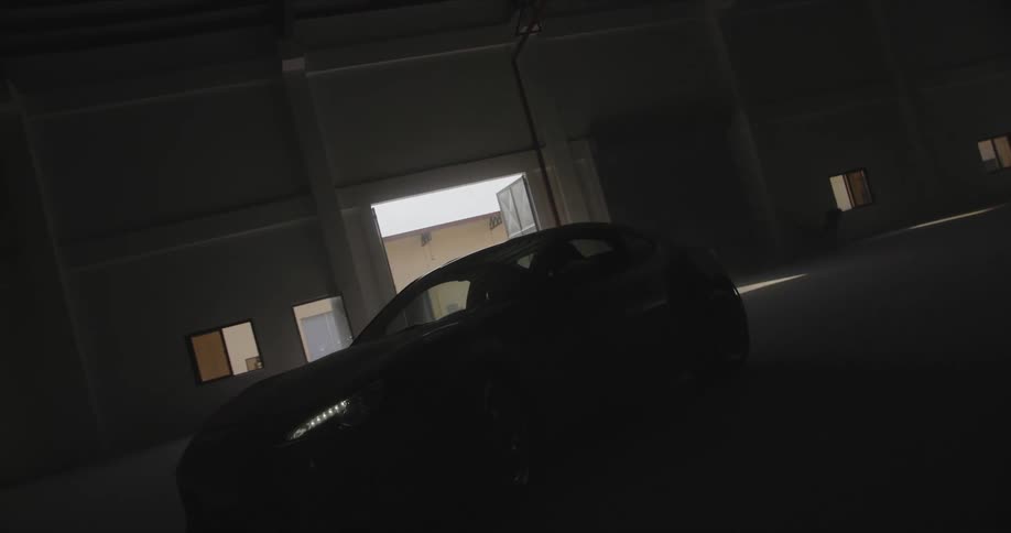 A person driving a car in a dark warehouse