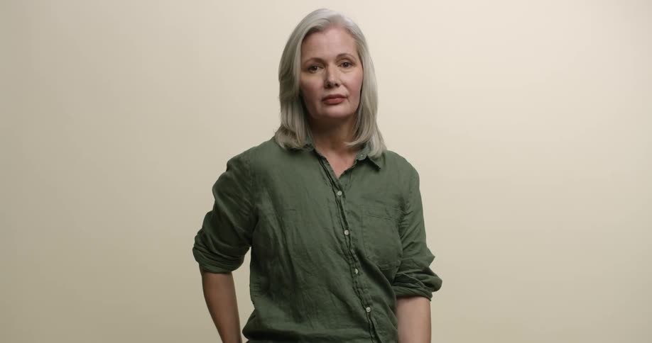 A mature white woman with gray hair sitting and posing for a portrait with no expression