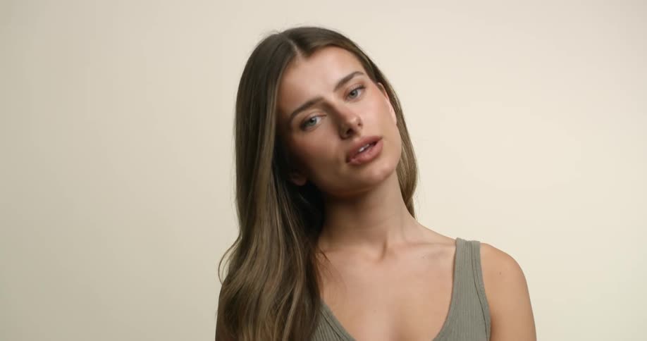 A young, white woman with light eyes and hair tilts her head back with her lips parted, as she poses for the camera.