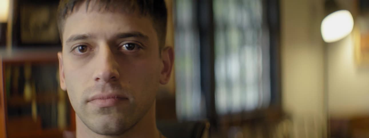 Shorthaired man turning to look into the camera standing indoors