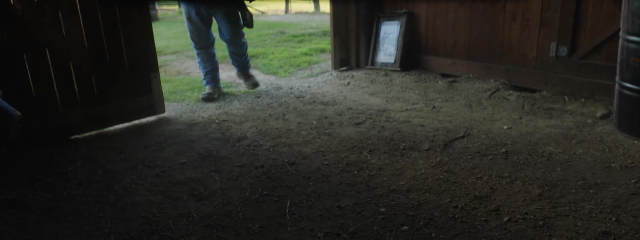 A man is opening a barn door outside