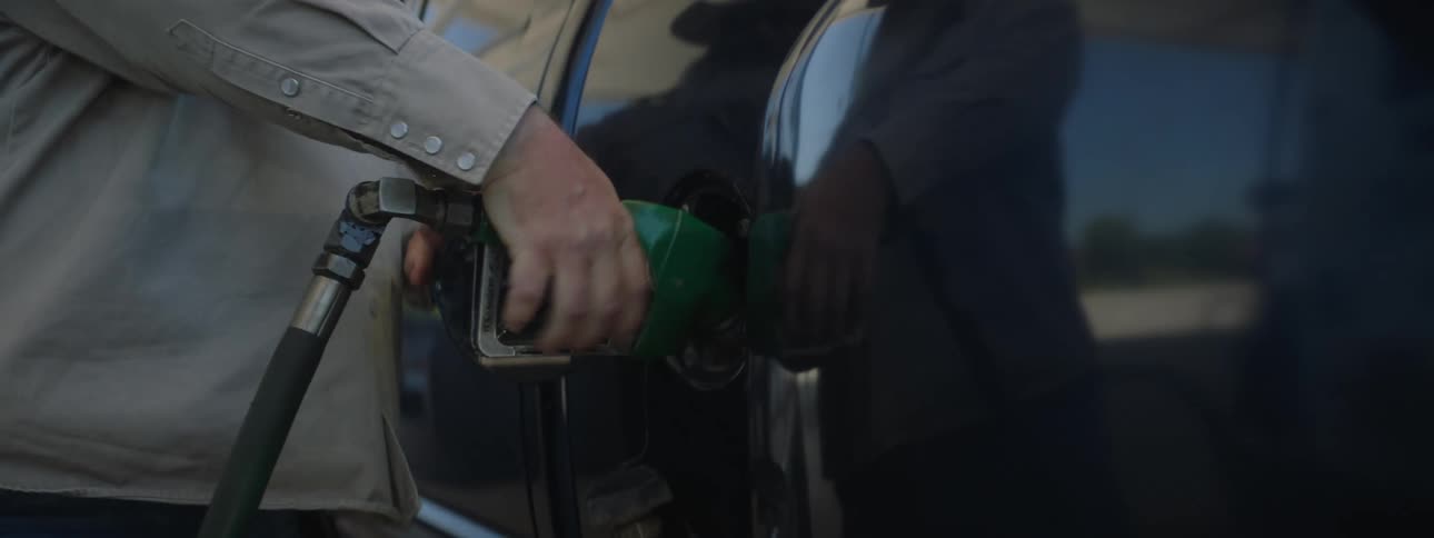 A man puts a gas nozzle in to his truck as he fills it up with gas