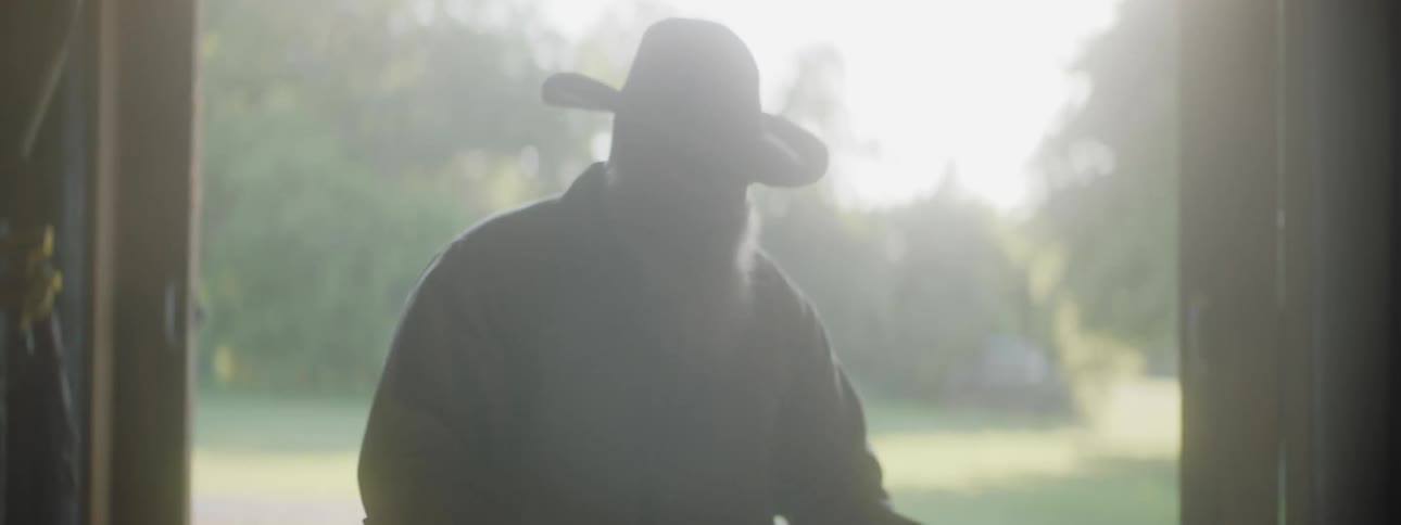A man with a hat and sunglasses stacking barrels in a barn