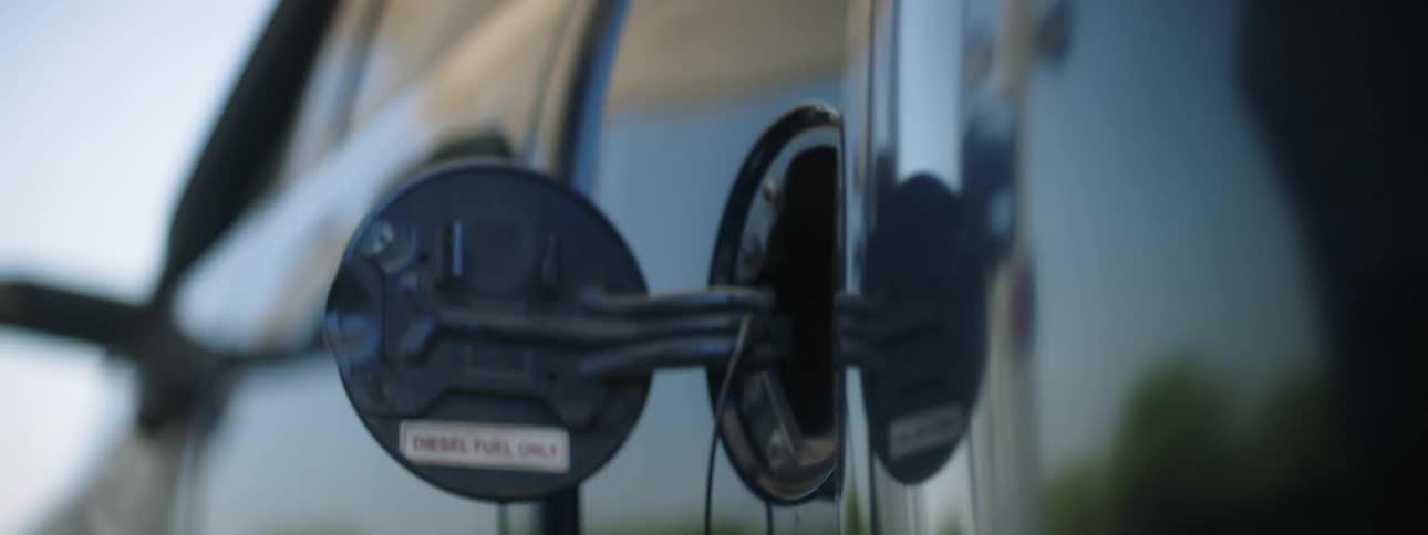 Someone fills their car with gas and removes the gas pump nozzle and then puts the gas cap on