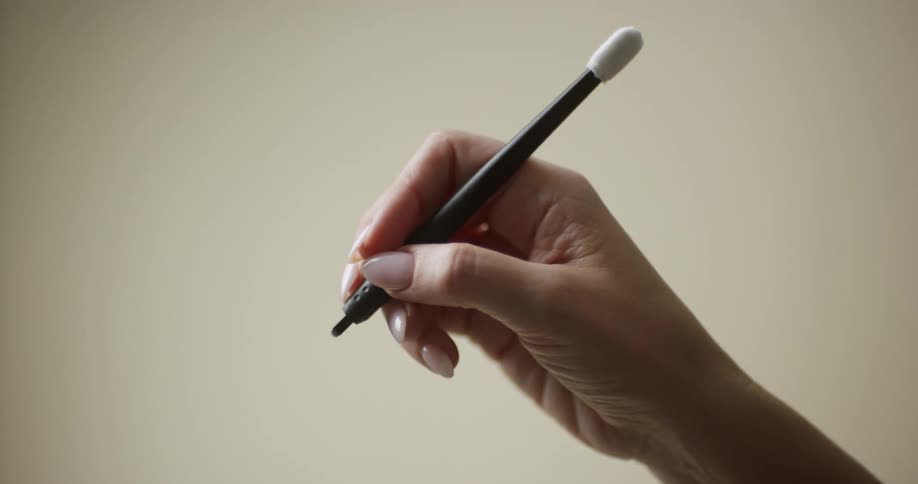 A manicured female hand holding and preparing to use a disposable manual microblading pen/hand tool/tattoo needle/blade.