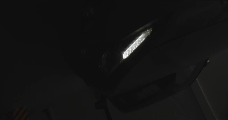 Black car with headlight on in the dark garage