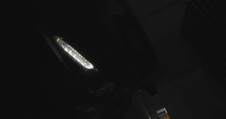 Black car with headlight and bonnet in dark garage