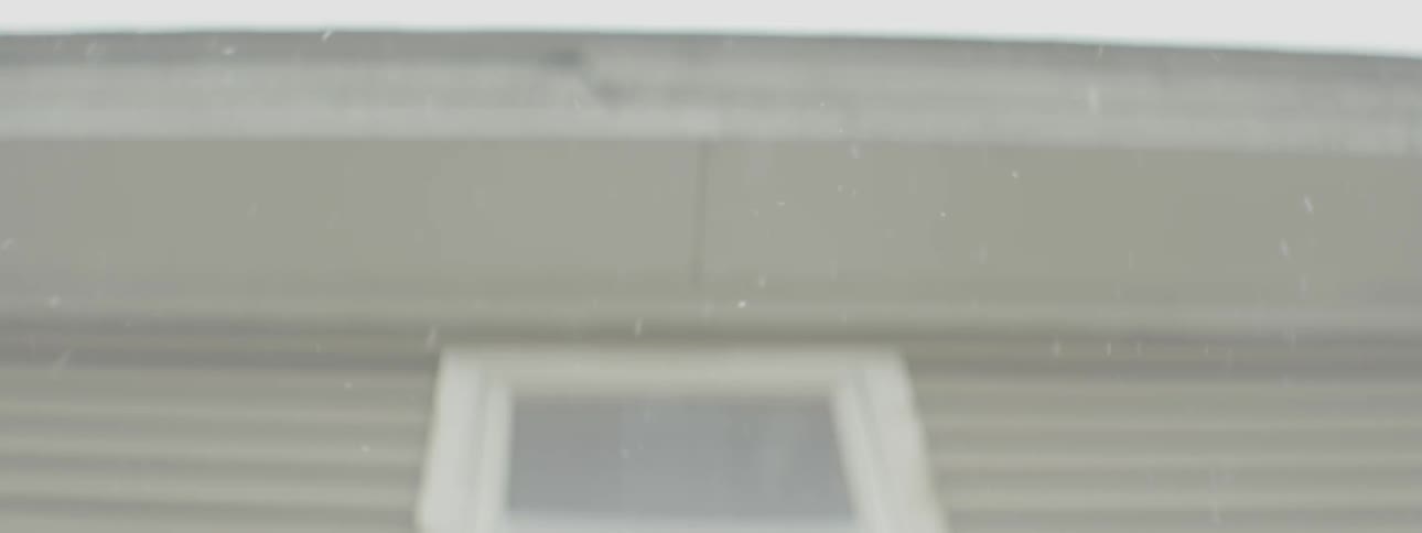 Light snow falling from above next to a house
