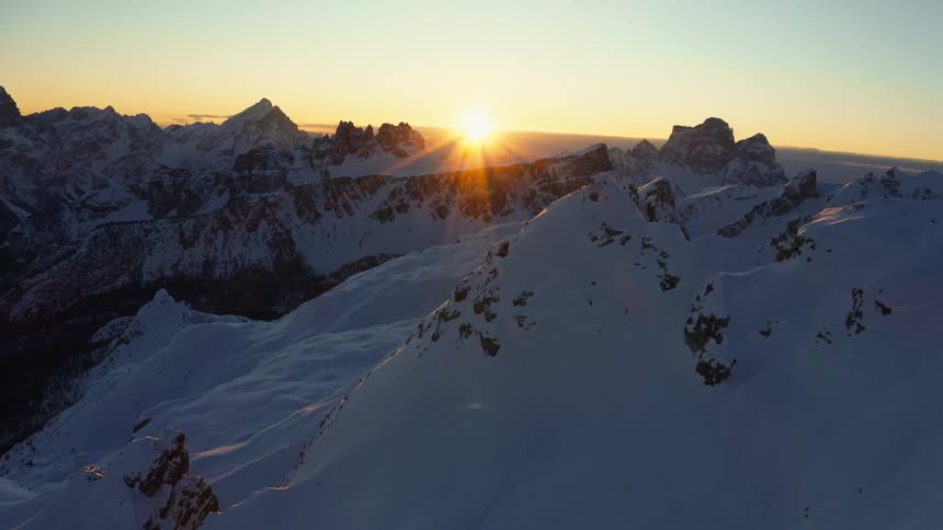 Aerial view of the snow slopes of a mountain range at sunset