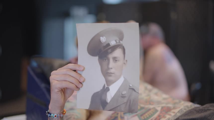 A man holds up a portrait of a soldier