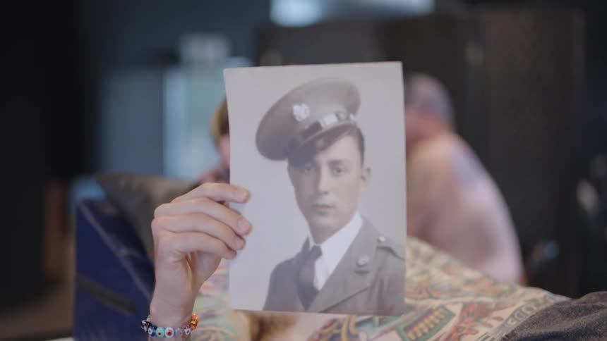 A woman is holding up an old photograph of a woman dressed in a military uniform