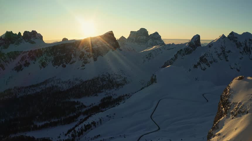 The sun is setting over a snow covered mountain range in the wilderness