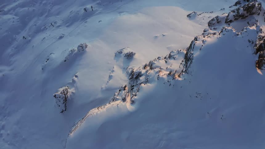 Trees peek out from under a thick layer of snow on a mountain