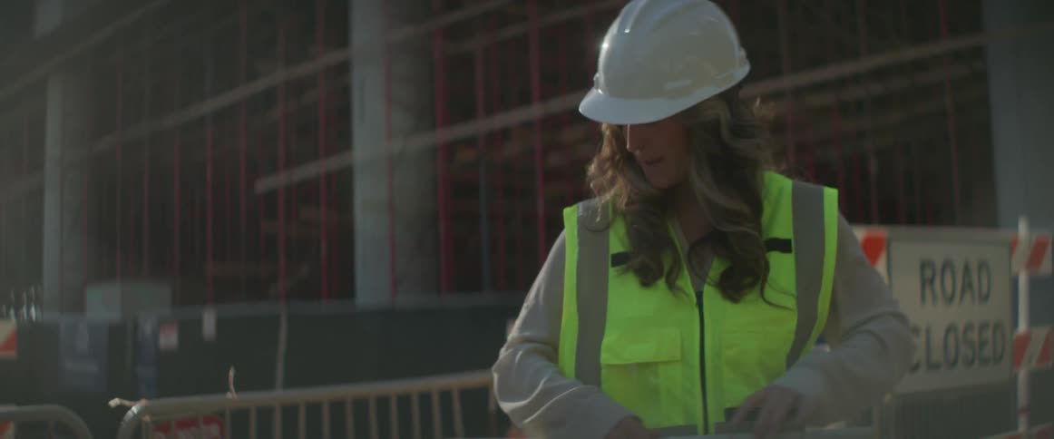 A woman construction worker rolling up a blueprint